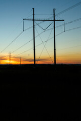 High voltage power lines in the light of the setting sun.