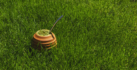 Yerba Mate tea on the grass. On a sunny day. Natural healthy drink. Green, fresh and refreshing. To...