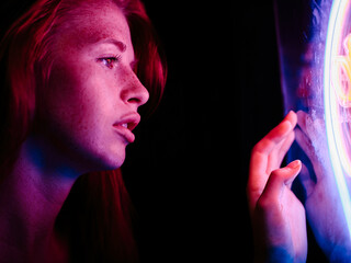 Close up of girl under pink neon light at night in profile