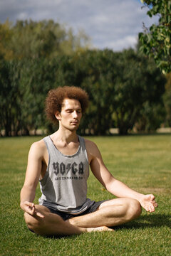 Young man meditating on lawn