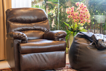 Interior design of house, home, villa feature leather couch,bean bag, artificial flower and a view of garden from living room
