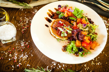Goat cheese salad. Strawberry-melon salad with chilli, apple-orange sauce, fig jam on white plate. Delicious meat food closeup served on a table for lunch in modern cuisine gourmet restaurant