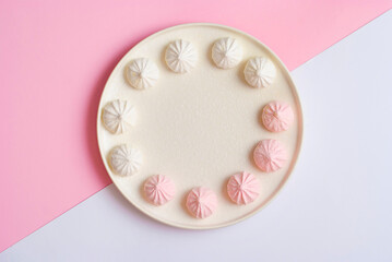 Pink and white plate with meringue sweet dessert cookies flat lay top view