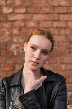 Portraits of a Russian teenager, with a brick wall in the background.