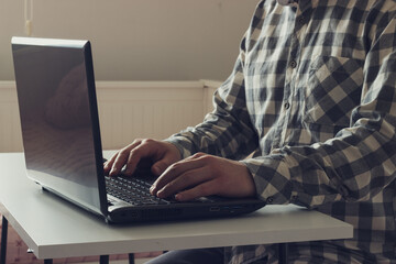 Fototapeta premium Caucasian young man is working with notebook in home. Man is typing on computer. Freelance work concept. Retro style.