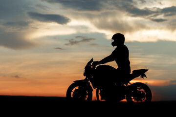 Fototapeta na wymiar Silhouette photo of biker driving motorcycle in sunset on the on country road.