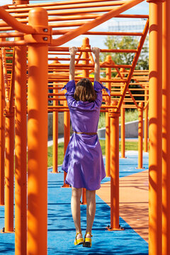 Stylish woman hanging on the horizontal bar