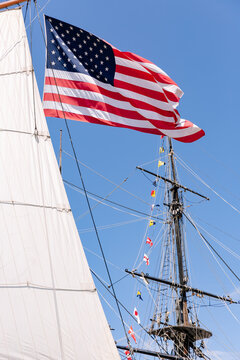 American flag waves in the sky while hanging from the mast of a sail boat.