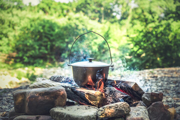Traveling, tourism, picnic cooking, cooking in a cauldron on the fire, boiling pot at the campfire...