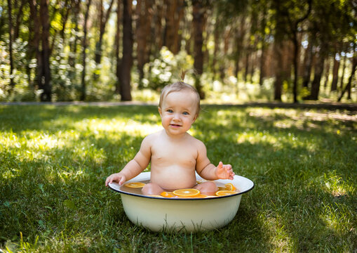Portrait of a happy little girl bathing in a bath on the green grass
