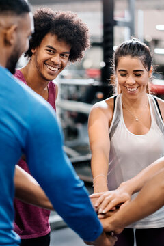 Group of sporty people putting their hands together showing unit