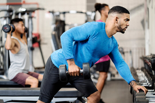 Muscular man working so hard on his biceps with a heavy dumbbell