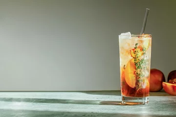 Foto op Plexiglas Refreshing peach iced tea Cuba Libre or Long Island iced tea cocktail in glass with straw. Summer refreshing fruit drink. Selective focus © daarnautova