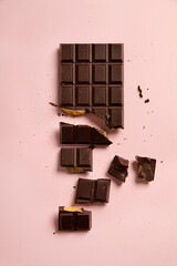 Block of dark chocolate and honeycomb on pink background