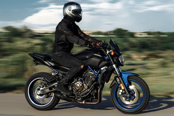 Motion photo of biker driving motorcycle in sunset on the country road.