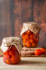 Jar with fermented tomatoes on wooden background. Homemade canned food.