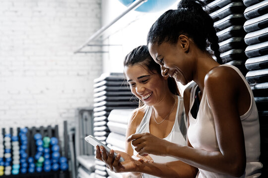 Two female partners ar resting on the floor watching some videos on a smartphone