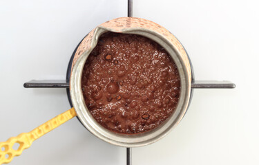 Top view of traditional Turkish coffee cooking on stove. Coffe in copper coffee pot. Concept of brewing coffee at home.