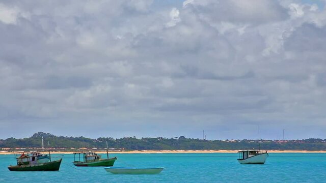 Artisanal fishing boats anchored on Coroa Vermelha beach, blue sea, sky with clouds