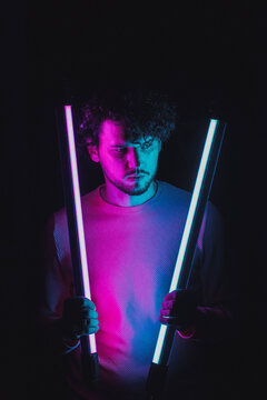 Sexy boy posing with fluorescent lamps.