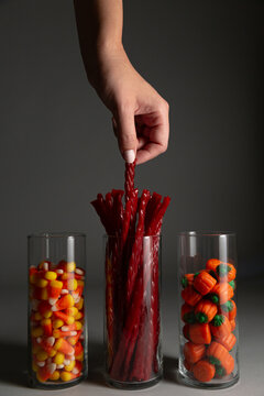 Anonymous female hand reaching for Halloween candy in glass jars.
