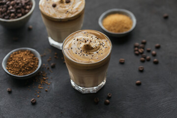 Glass of Iced Dalgona Coffee, trendy fluffy creamy whipped coffee and milk on black background.