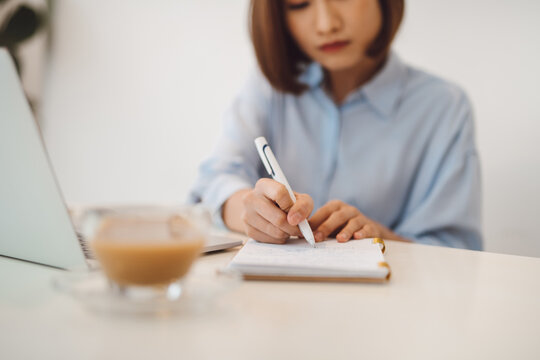 Beautiful woman think and write notes on paper working on a laptop freedom from office at home