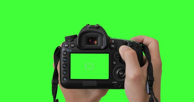 Professional photographer or filmmaker adjusts the DSLR camera settings before shooting. Isolated gear is holding by two hands. Keyed green screen.
