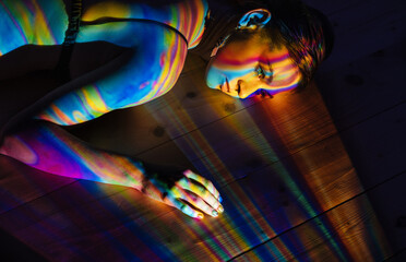 Model lying on floor under multicolored illumination