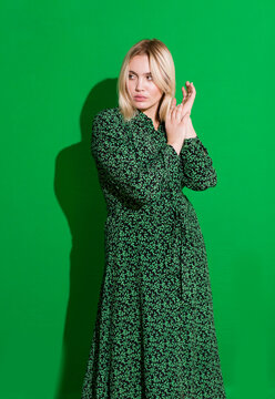 Beautiful blonde plus size woman in green dress on green background