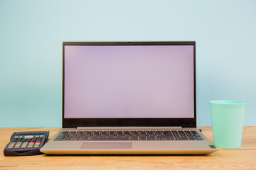 Fototapeta premium Laptop computer with a white screen on the desktop, blue background. Business and finance