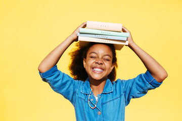 Happy African American girl balancing books on head