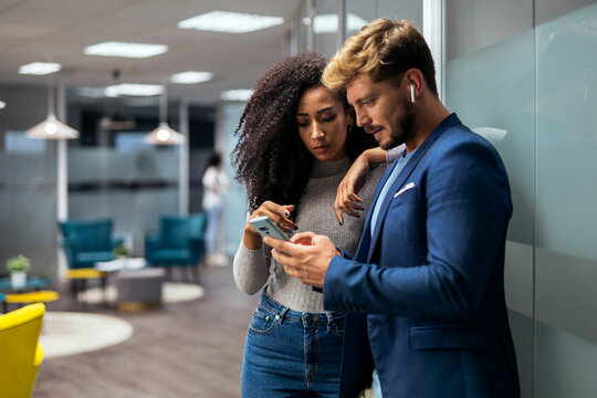 young modern people in smart casual wear discussing business an looking at screen phone for a project