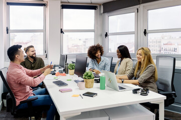 Young coworkers looking at a african american woman listening to