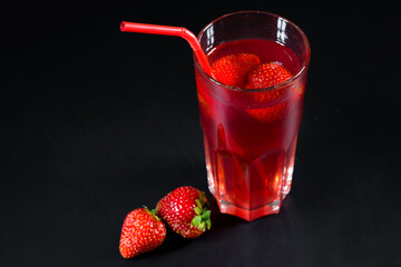 Strawberry lemonade and strawberries on a black background. Side view.
