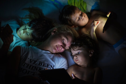 Mother with her kids using digital tablet in the dark