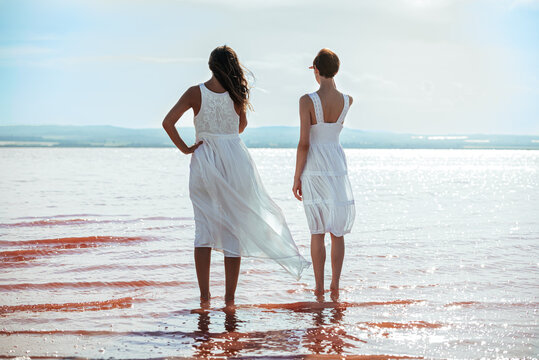 cute Women wearing white dress standing on a amazing pink lake