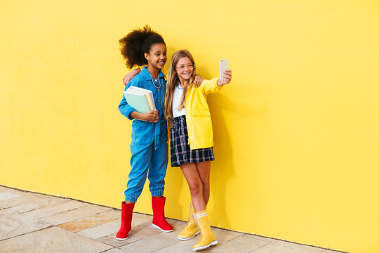 Multiethnic cheerful girls taking selfie during studies