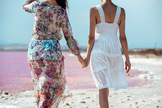 back view of cute Women walking on a amazing pink lake