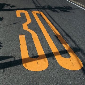 Thirty kilometers per hour speed limit sign on an asphalt road.