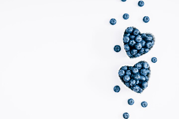 Plate in shape of heart with blueberries on white background. Blueberry berries background. Valentine's Day. Flat lay, top view, copy space