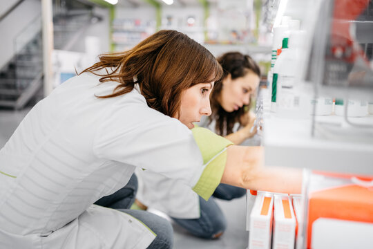 Female pharmacists setting in order products of the drugstore