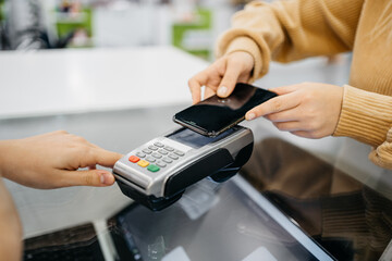 Detail of a client hands paying with the smartphone at a pharmacy