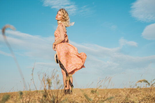 Sensual Blond Woman Wearing Silk Dress Outdoors Against The Blue Sky