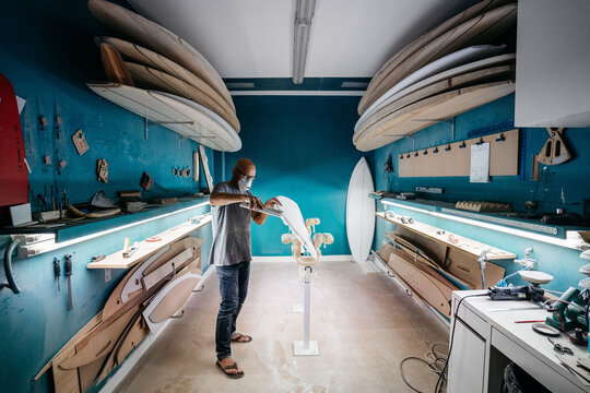 Overview of a shaper making a surboard in his workshop