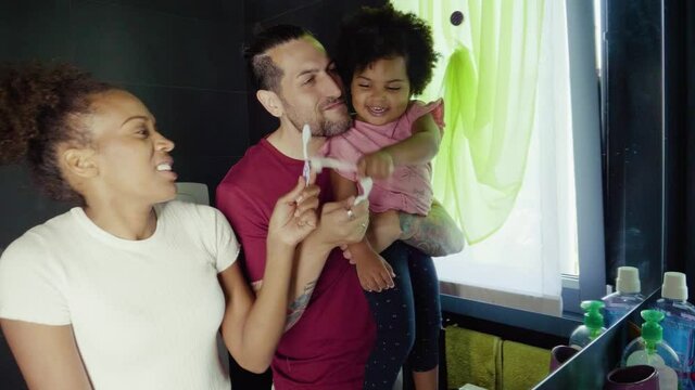 Family Brushing Their Teeth In Bathroom