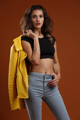 A girl in a black top, blue jeans and a yellow jacket