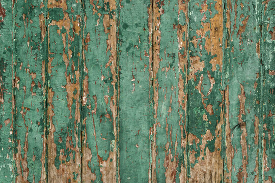 Old wood wall with green paint peeling and chipping away.