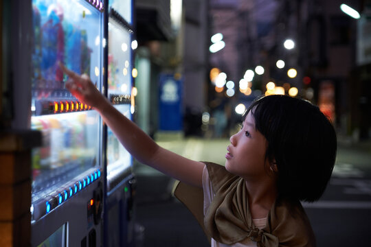 Asian little girl in front of a drink vending machine, on the streets of Kyoto, Japan