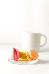 delicious delicate multicolored macaroons on a platter with a cup of coffee in the background with place for text. close-up. selective focus.